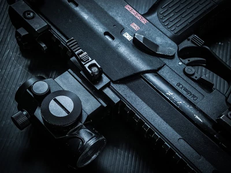 Close-up of an HK MP7-style firearm receiver showing the compact gas-operated action and top Picatinny rail