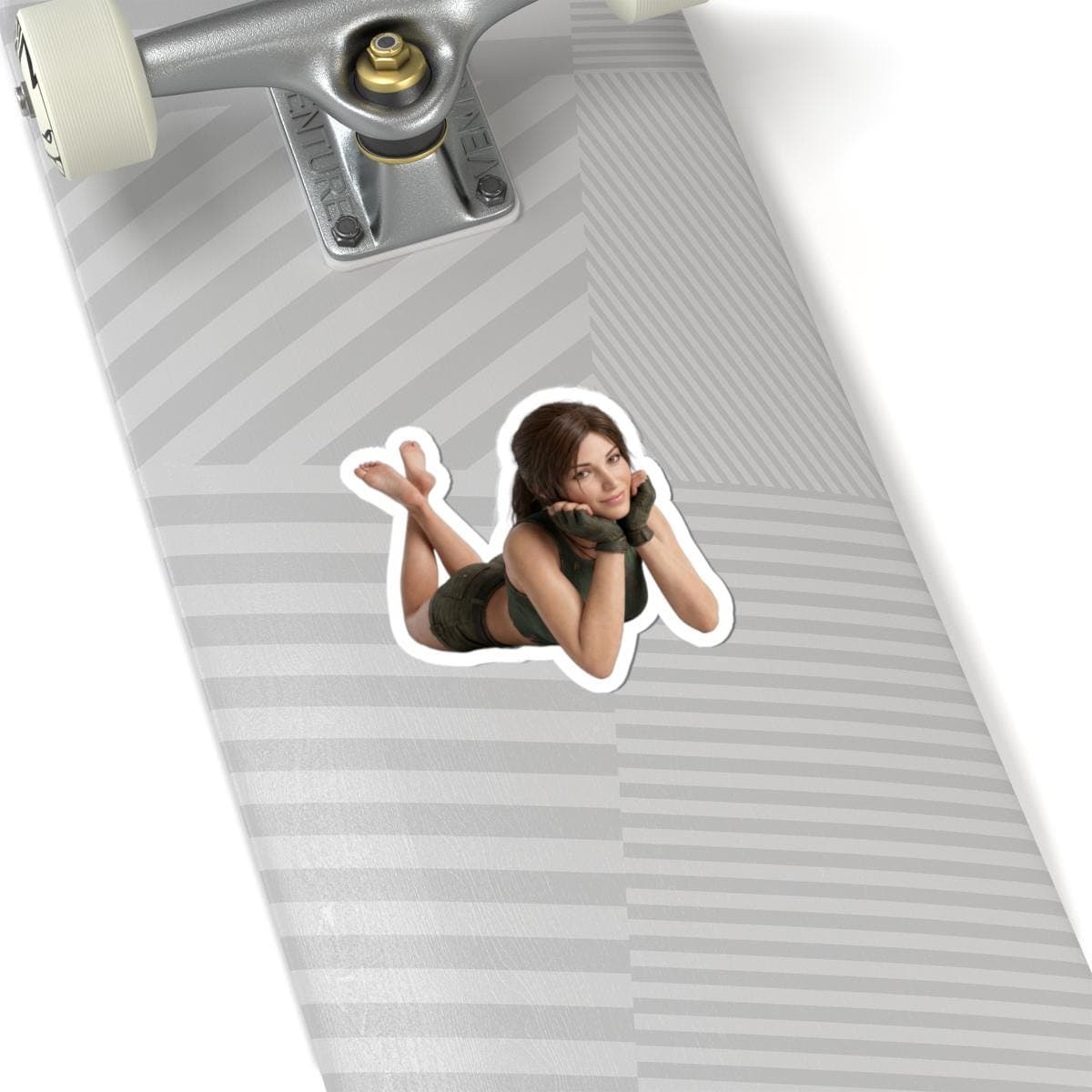 May include: A die-cut sticker featuring a woman in a green outfit, lying down with her hands under her chin. The sticker is placed on a skateboard.