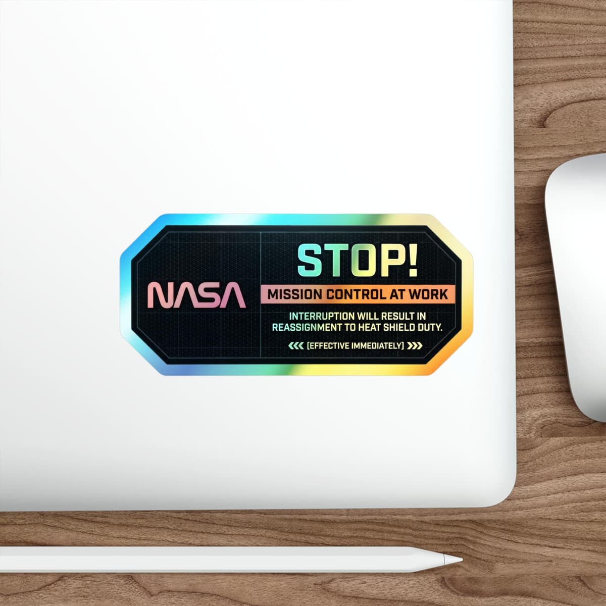 May include: A rectangular sticker with a holographic border and the text "STOP! NASA MISSION CONTROL AT WORK." Additional text warns of reassignment to heat shield duty. The sticker is on a white surface.