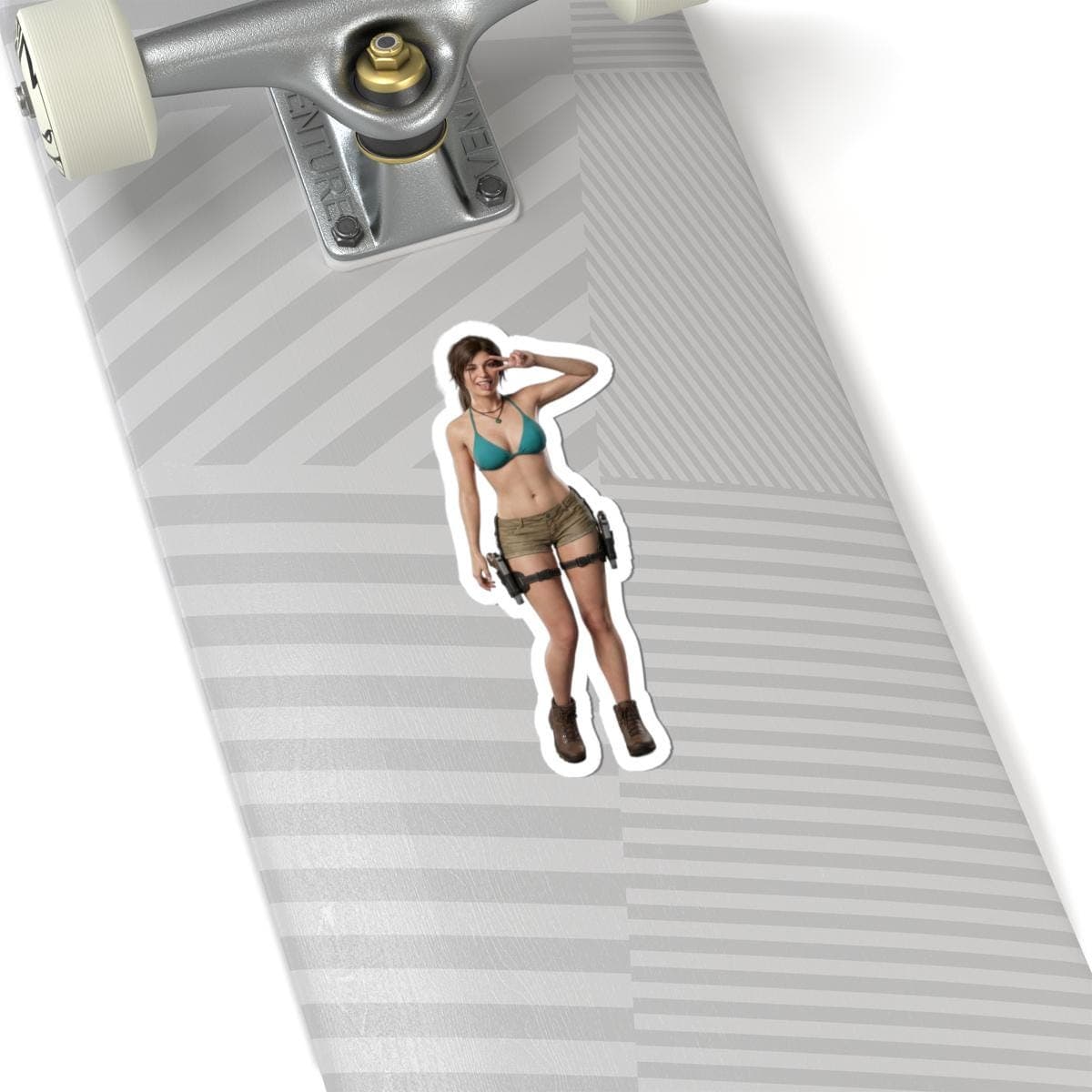 May include: A sticker featuring a woman in a teal bikini top, khaki shorts, and brown boots. The sticker has a white border and is placed on a skateboard.