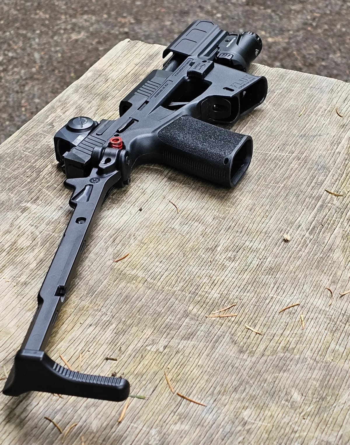 SIG P365-FLUX TACKIT with brace fully deployed, laid across a wood shooting bench