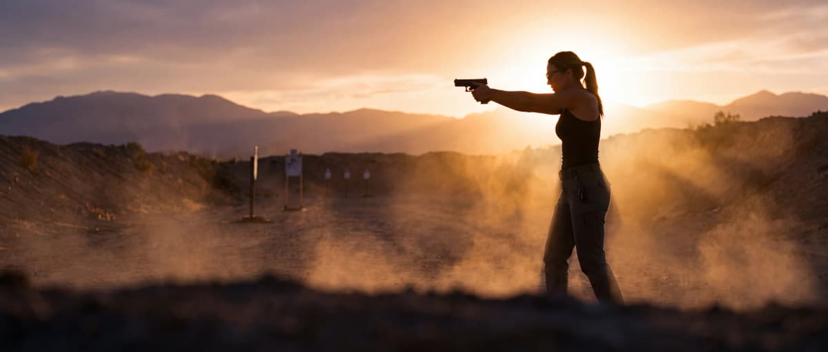 Shooter pressing out a Glock-pattern pistol at a desert range at golden hour