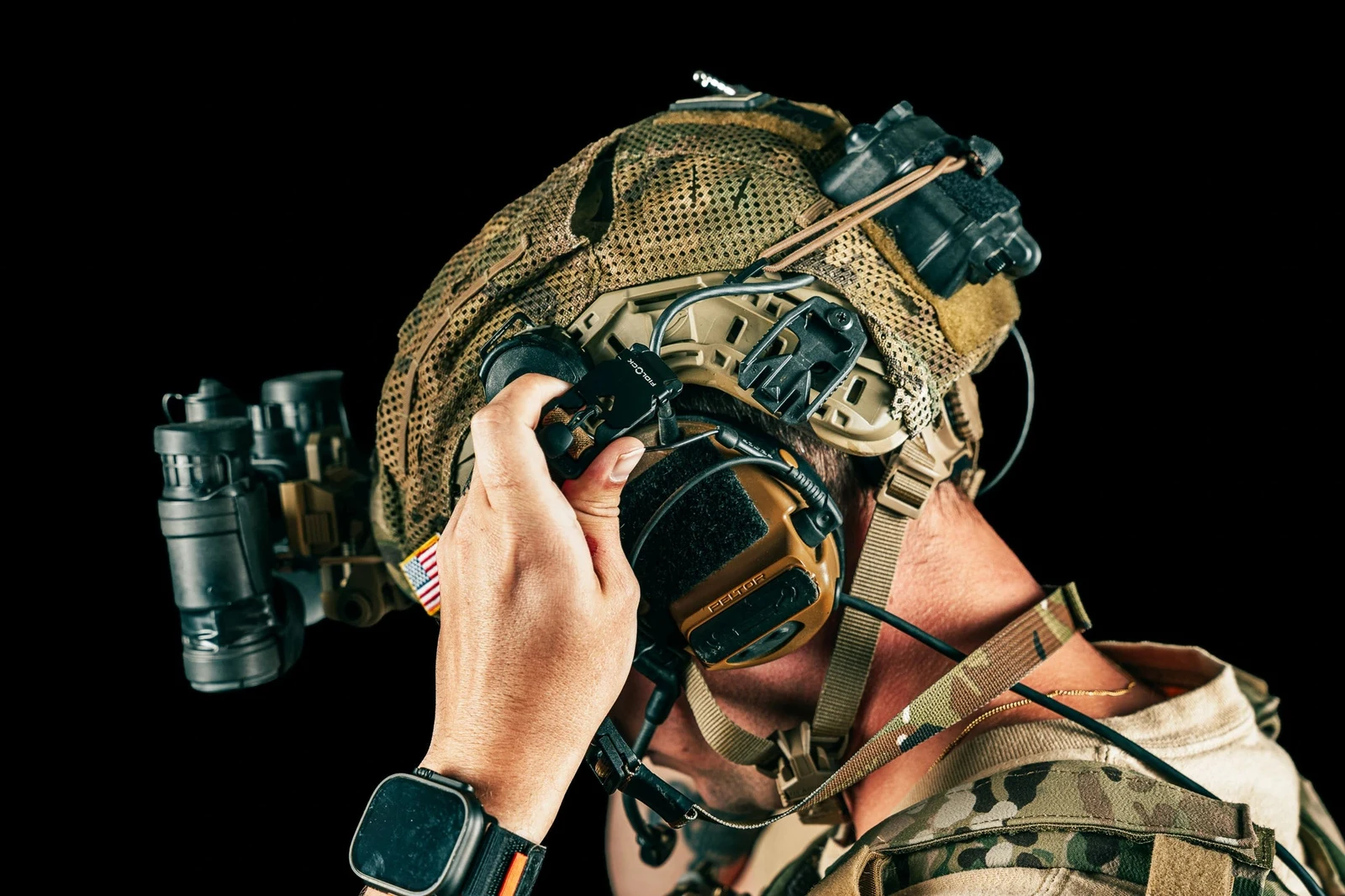 Operator reaching up to release the Fidlock connector on the side ARC rail of a covered helmet while a night vision device stays mounted on the front shroud
