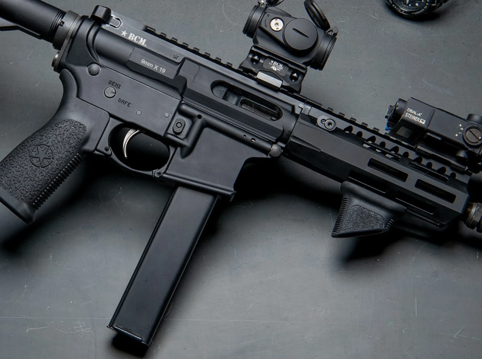 Close crop of Bravo Company's BCM9 teaser photo showing the 9mm X 19 magwell rollmark above a straight steel stick magazine