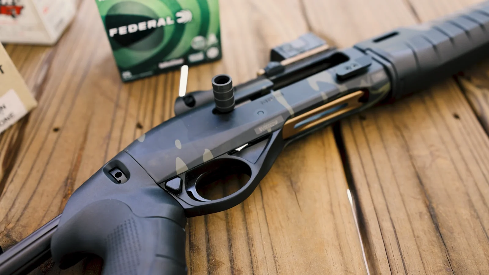 MultiCam Black Benelli M2-G1 Tactical on a wooden bench beside a box of Federal 12 gauge shells