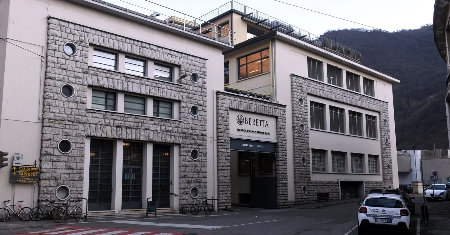 Stone and stucco facade of the Fabbrica d'Armi Pietro Beretta plant in Gardone Val Trompia, Italy, with the Beretta name over Gate 1