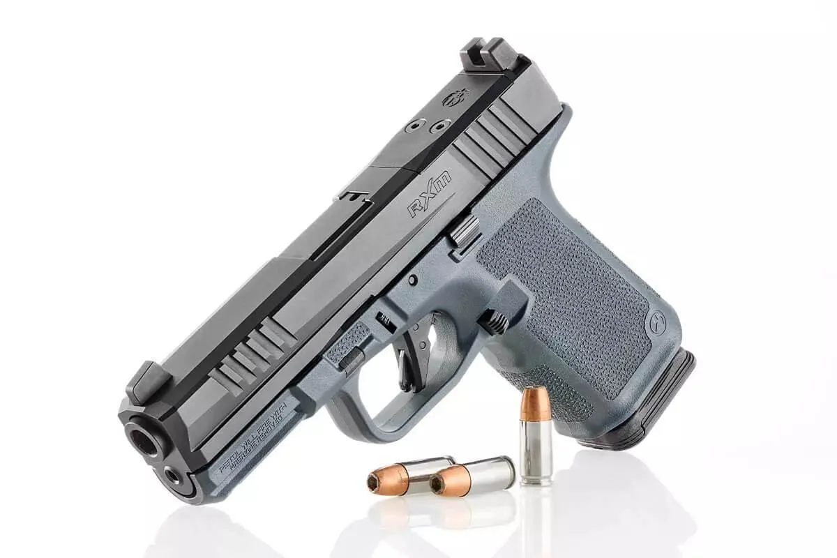 Ruger RXM striker-fired 9mm pistol with a grey Magpul frame and black slide, staged with three hollow point cartridges