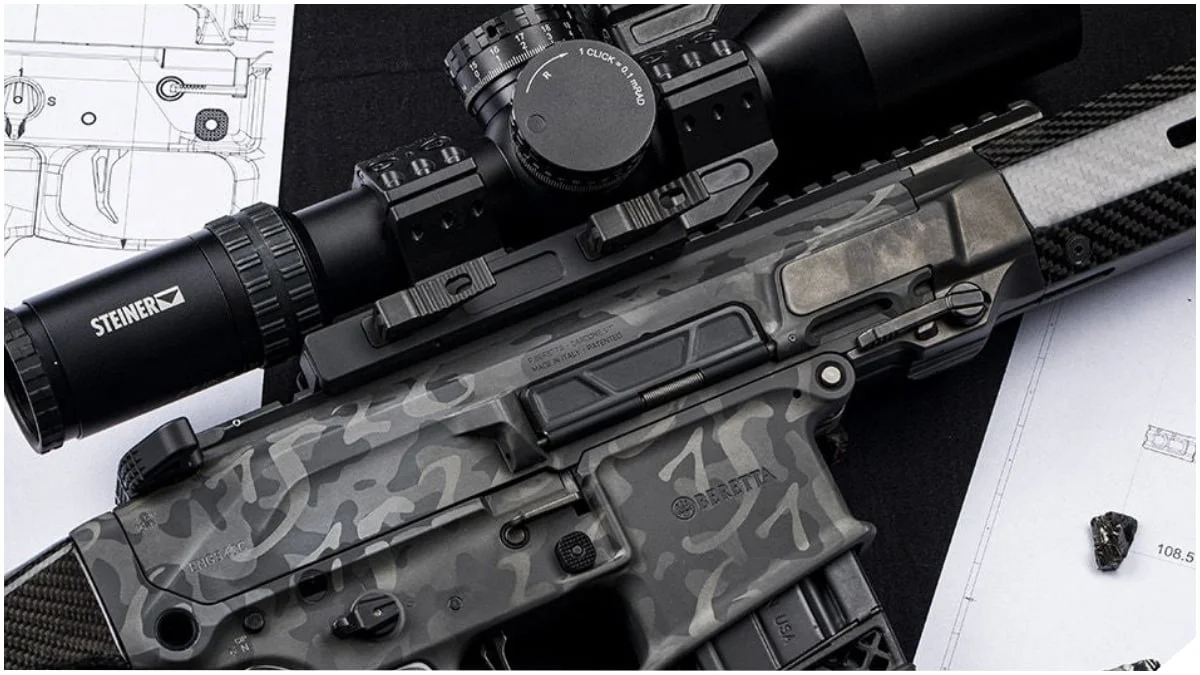 Close-up of the Beretta Titan upper receiver showing the gray camouflage finish, 1526 founding date pattern, and mounted Steiner optic