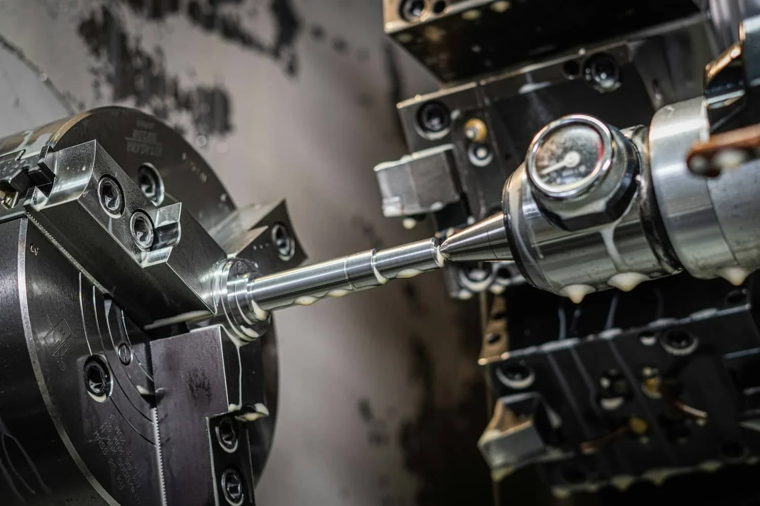 A barrel blank held in a lathe chuck with cutting fluid running over it as the tool works the muzzle end