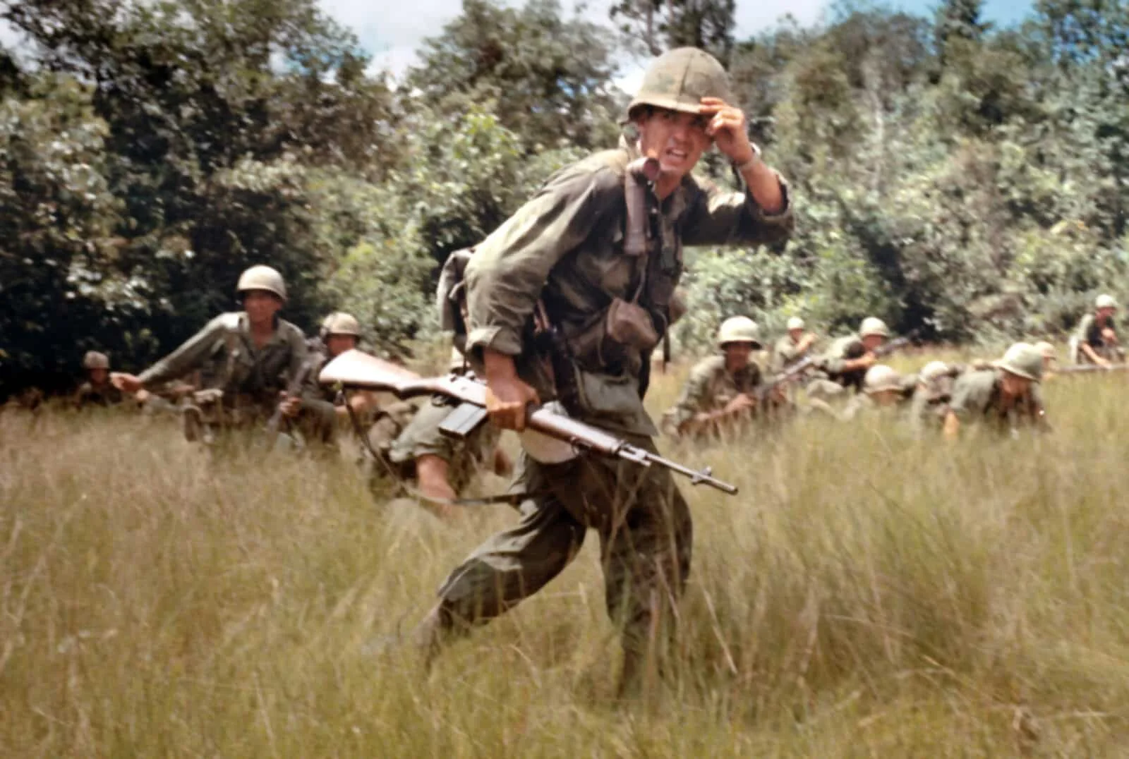 U.S. soldiers advancing through tall grass carrying M14 rifles during the Vietnam War