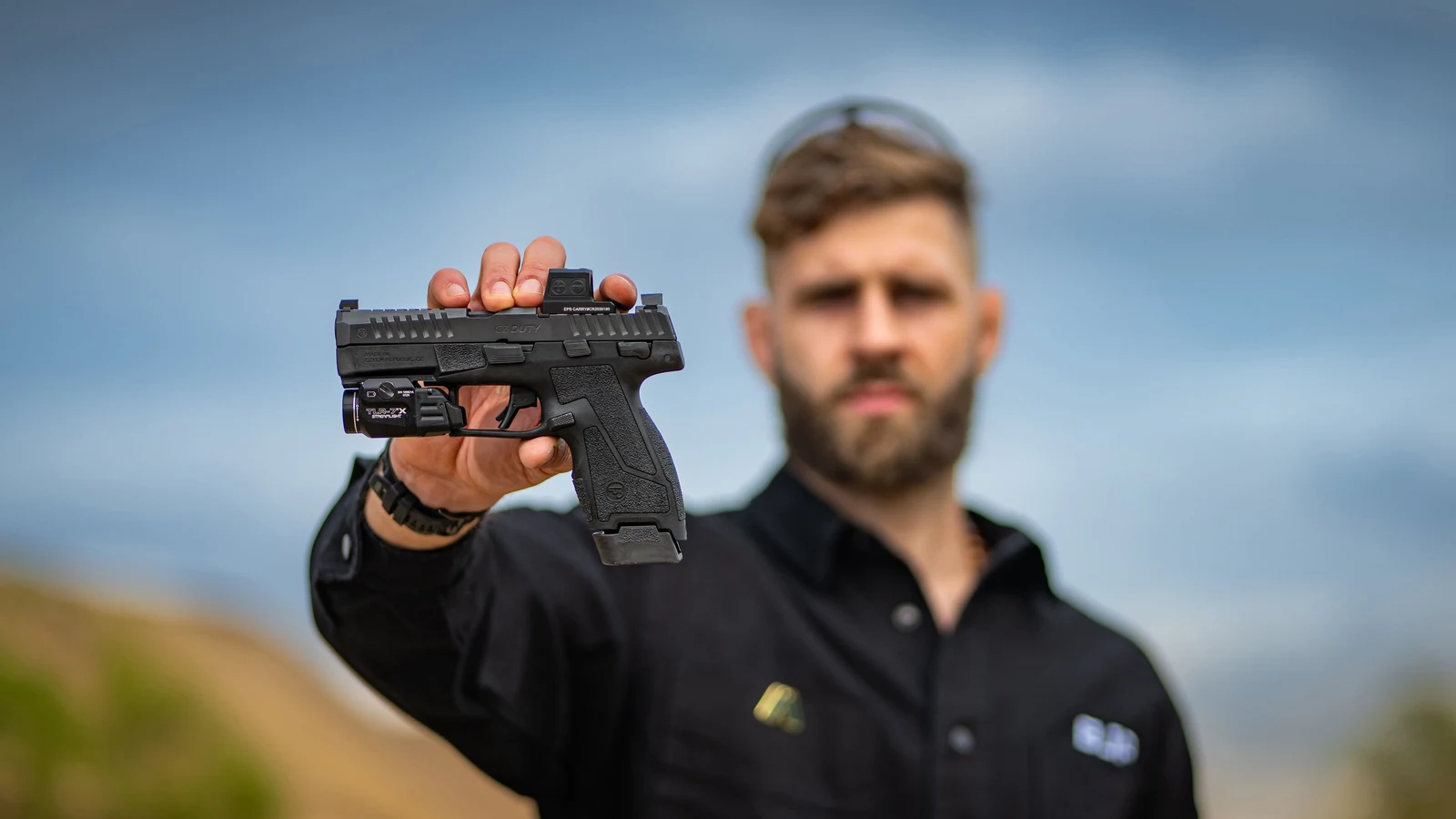 CZ Duty Compact held at arm's length with a red dot sight and weapon light mounted