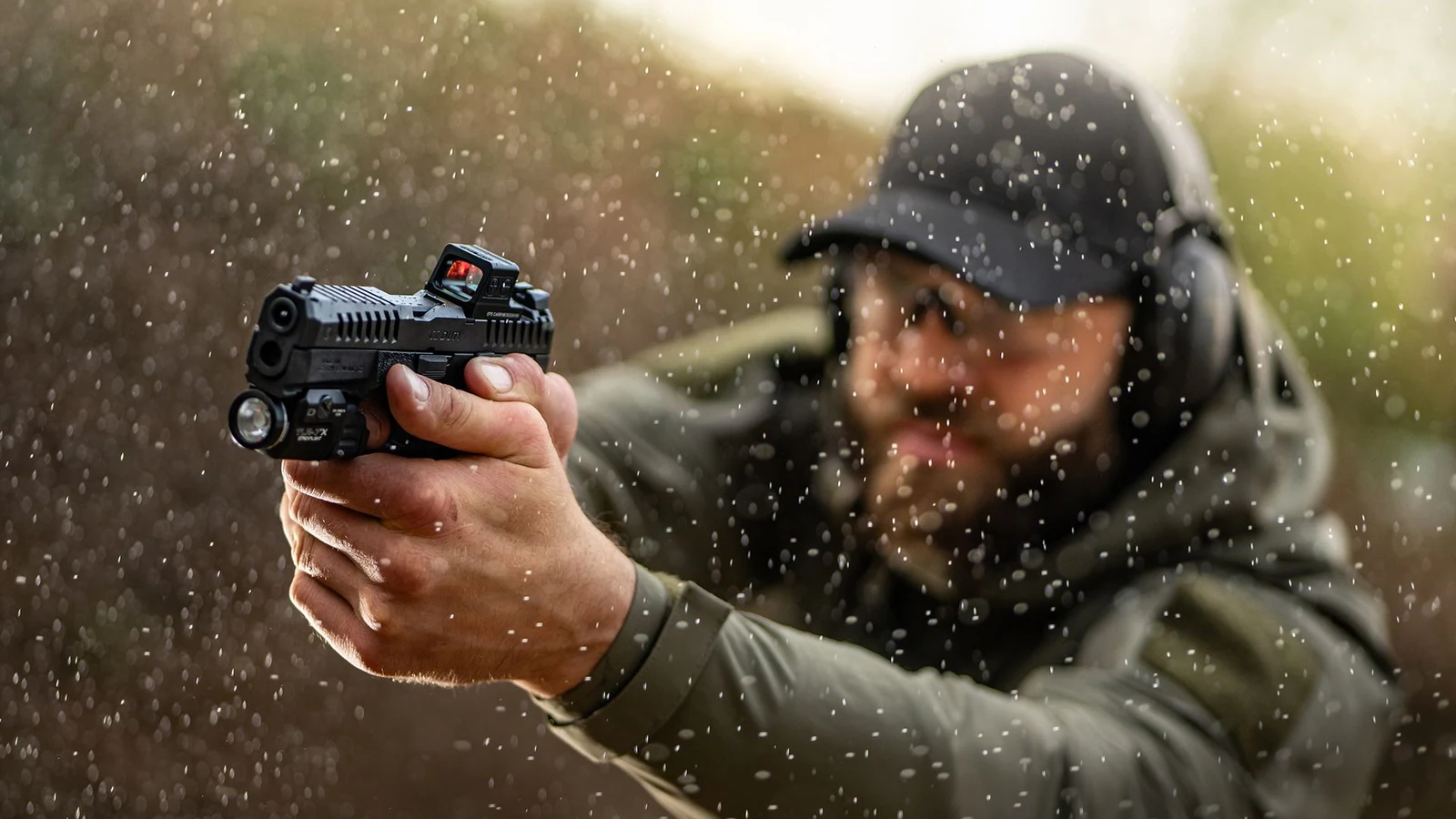 Shooter firing a CZ Duty with a slide-mounted red dot and weapon light in heavy rain
