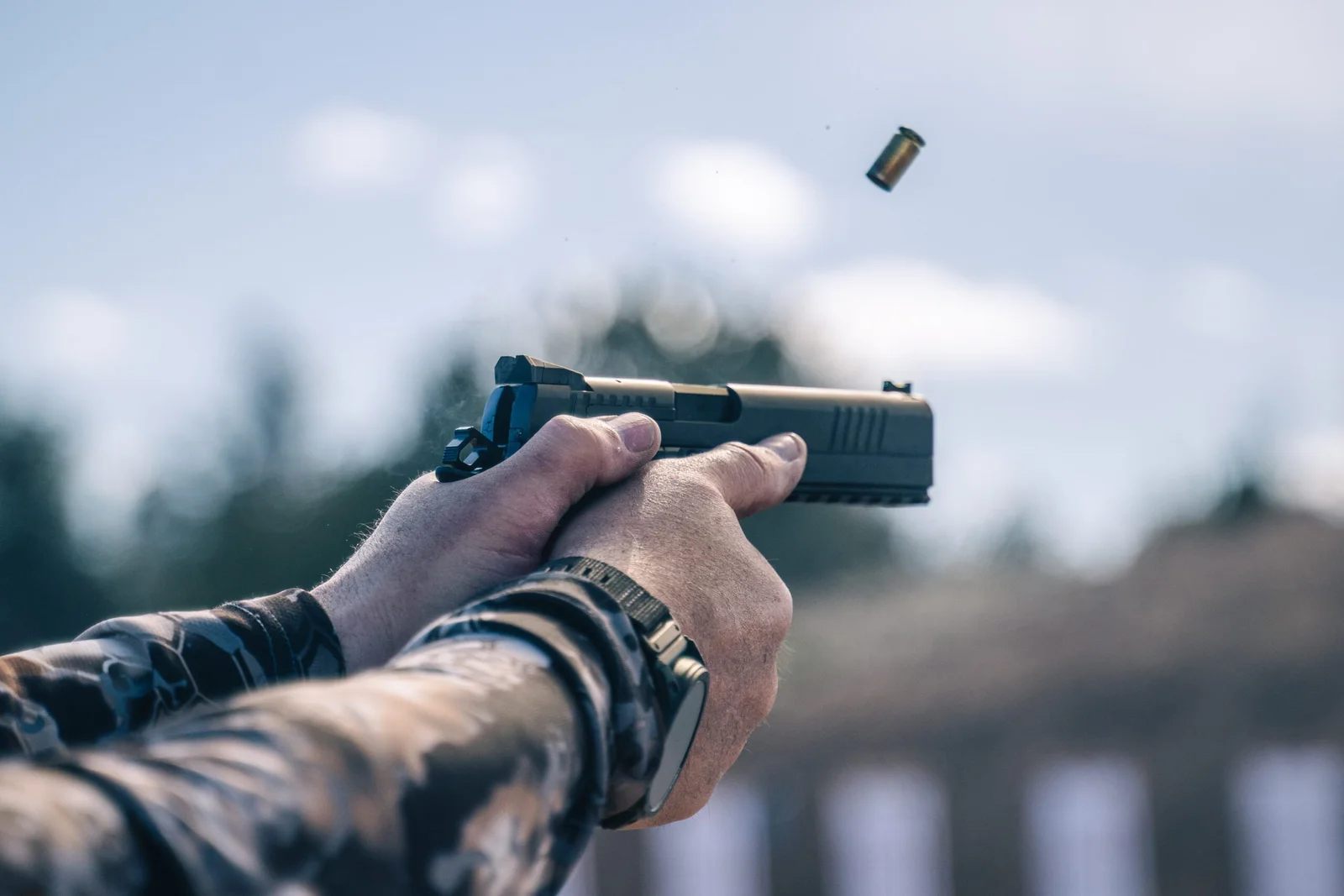 Shooter firing the Dan Wesson DWX competition pistol at an outdoor range with the slide cycling