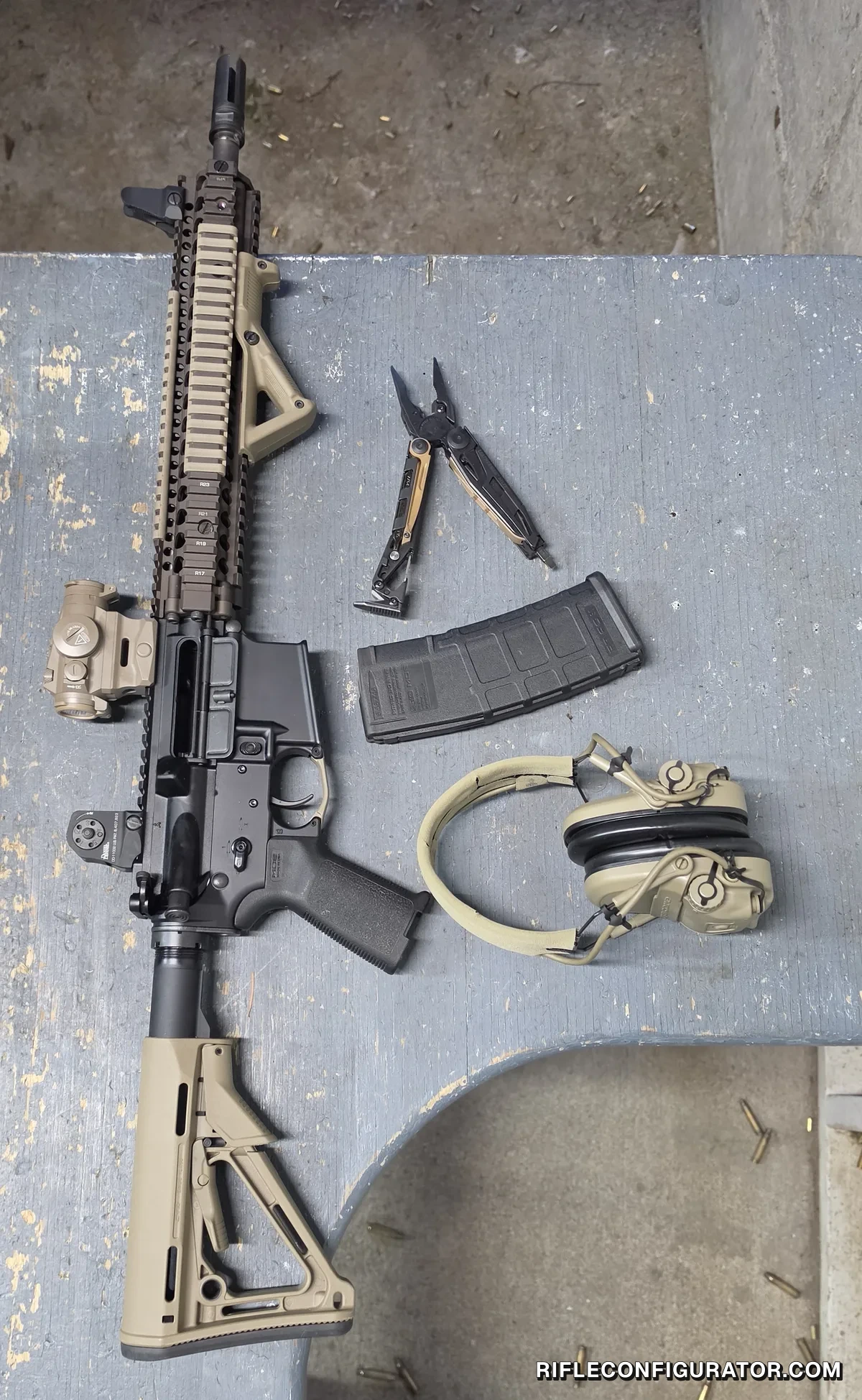 Overhead flat lay of the Block II carbine with its magazine removed, laid out on a range bench beside a PMAG, electronic ear protection, and a multitool, with spent brass on the concrete floor
