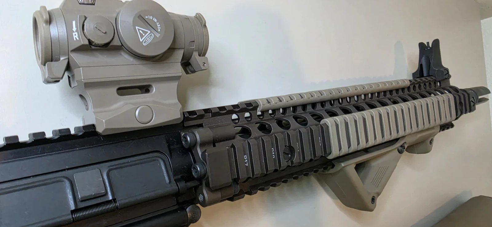 Close-up of a Daniel Defense RIS II quad rail in FDE with a flat dark earth micro red dot on the upper receiver and a folding front sight at the rail's end