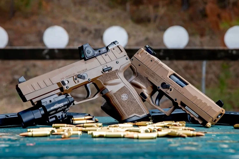 FN pistols with red dot sights on a shooting range with spent brass