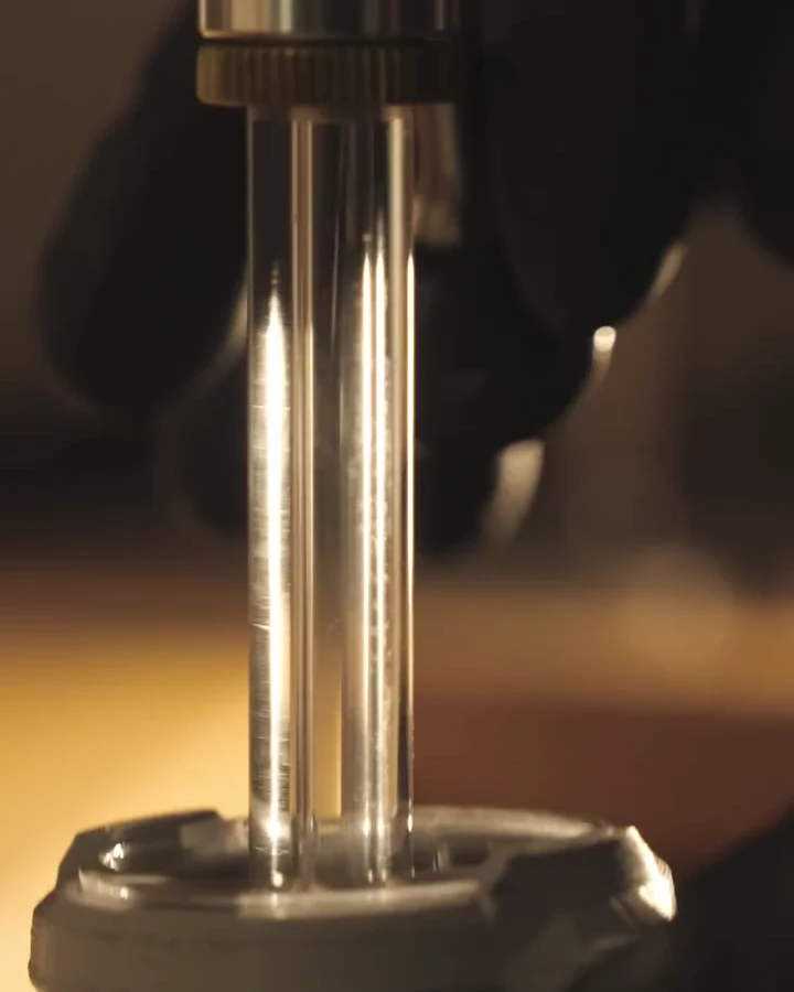 Close-up from Geissele's HICAR teaser video showing a cartridge case in a clear loading tube on precision loading equipment