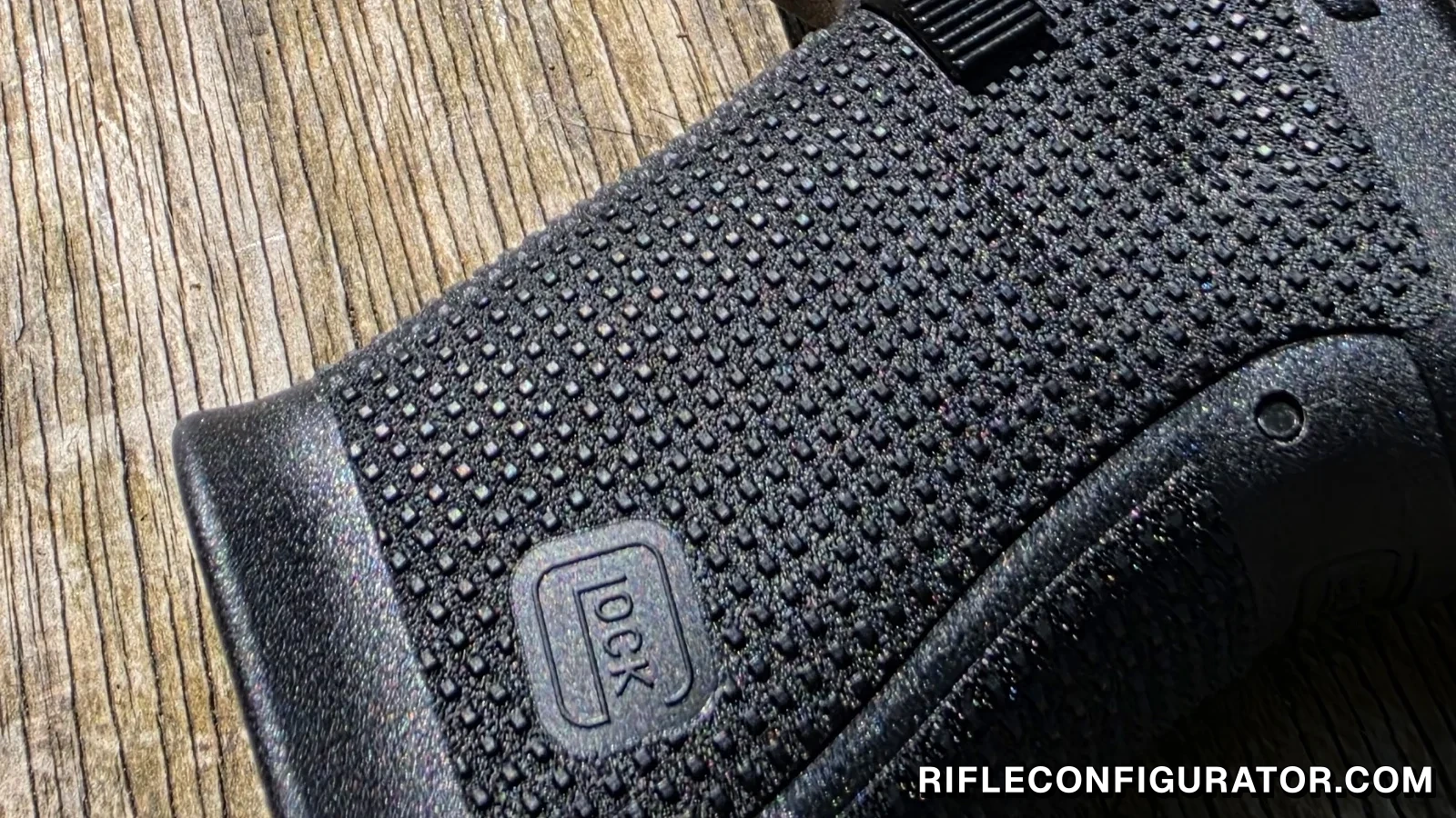 Macro view of a worn Glock 19 Gen6 grip panel, showing gaps in the RTF6 grid where individual texture studs have torn off, with ragged stubs beside them, while the studs around the Glock logo remain crisp and square