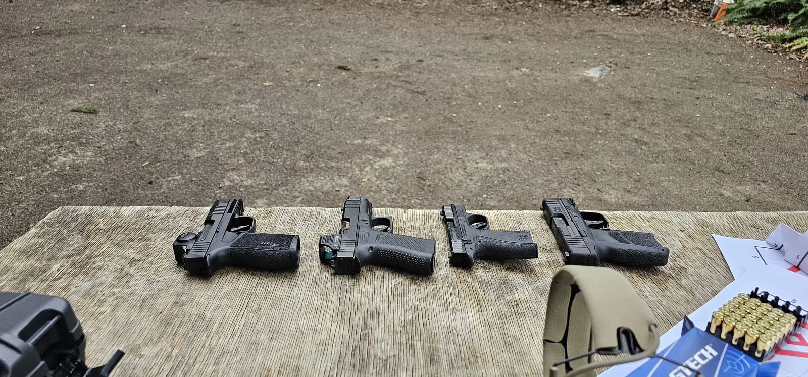 The HK CC9 and competing micro-compact pistols laid out on a range table with a box of 9mm