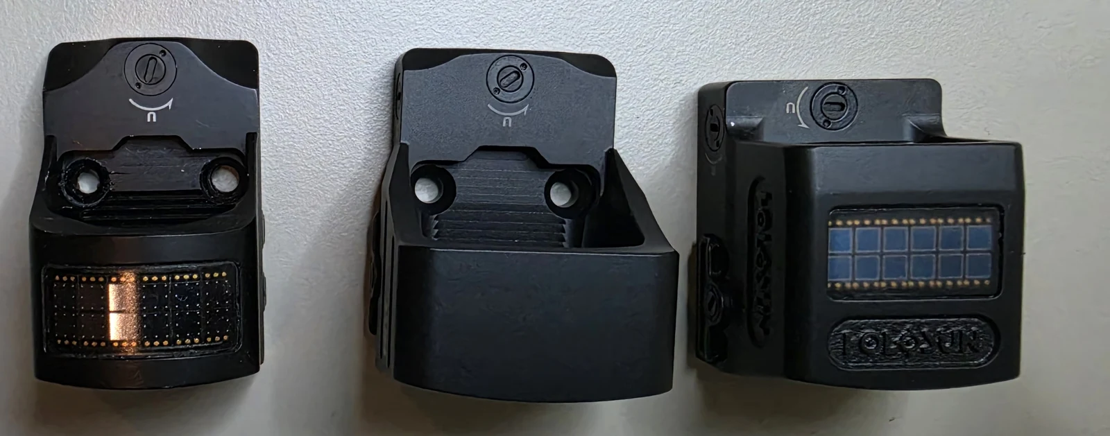Undersides of three Holosun optics showing solar panels on the outer two and no panel on the 507COMP