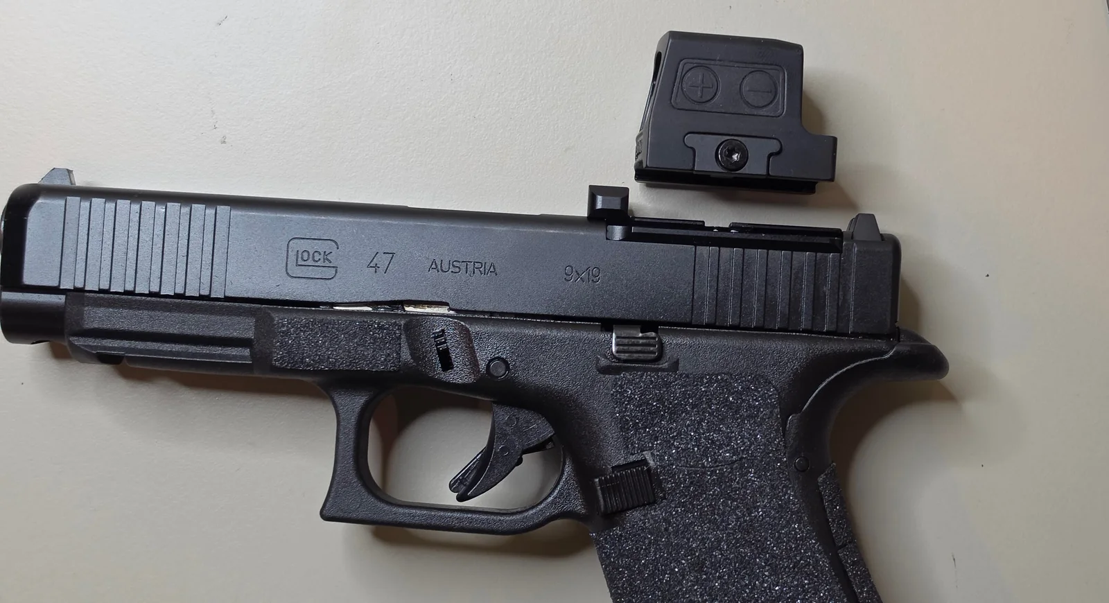 Glock 47 slide with the MOS adapter plate installed and the Holosun 509T X2 Gold sitting off the gun beside it