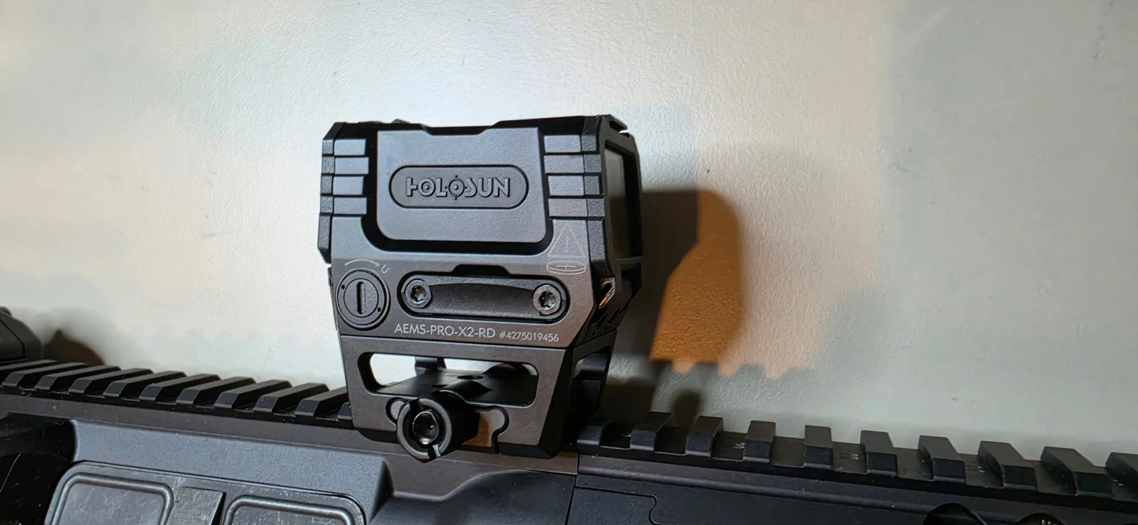Rear three-quarter view of the Holosun AEMS Pro X2 showing the AEMS-PRO-X2-RD model stamp, the stepped housing cutouts, and the four-post mount clamped to a Picatinny rail