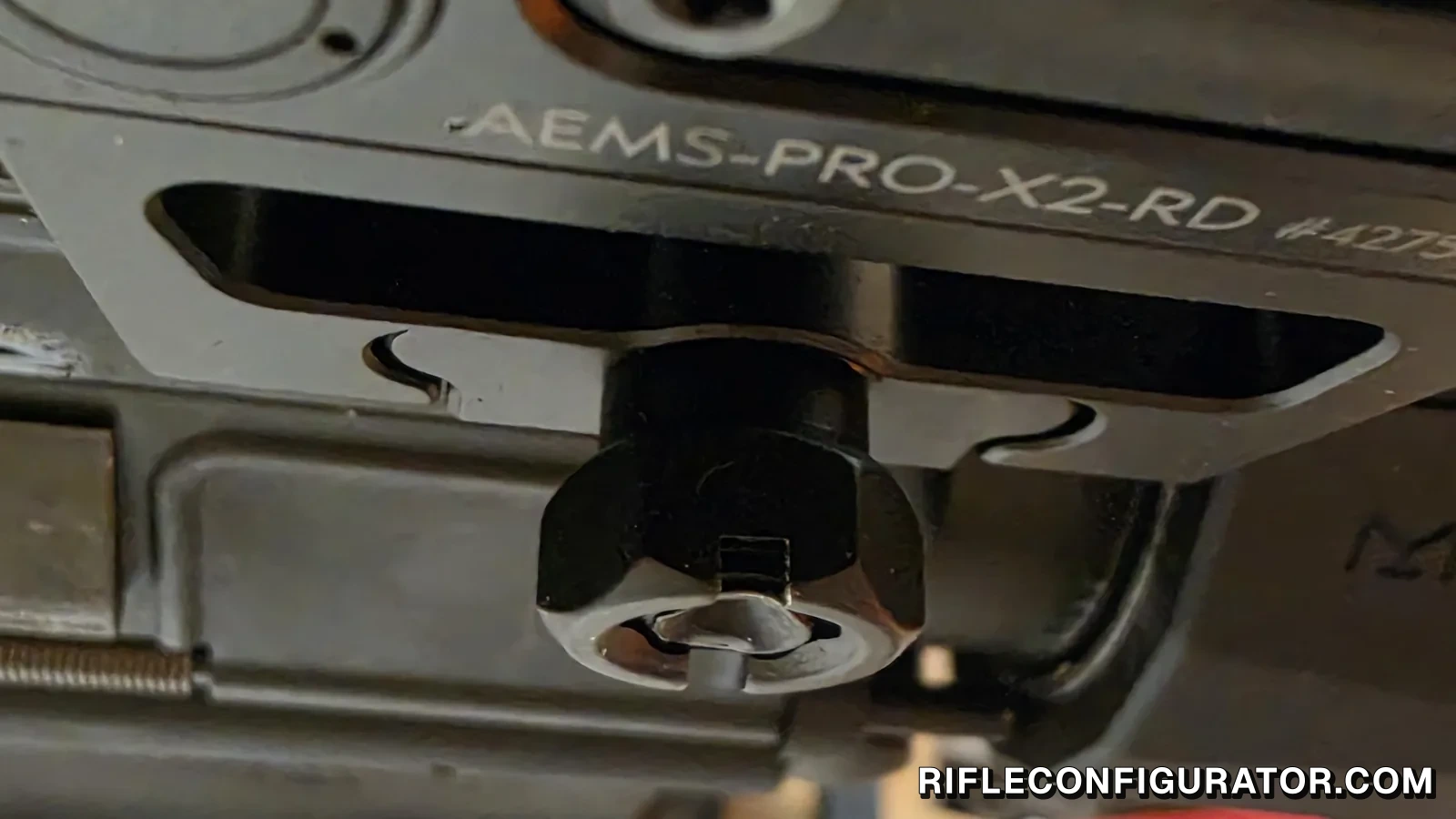 Underside of the Holosun AEMS Pro X2 mount clamped to a Picatinny rail, showing the 11mm hex clamp nut with the cross bolt protruding through the middle of its slotted face