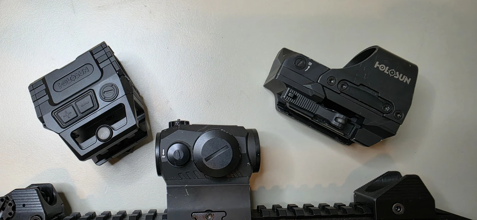 Holosun AEMS Pro X2 at left beside a SIG Romeo 5 micro red dot and a Holosun 510C open-emitter reflex sight, all dismounted