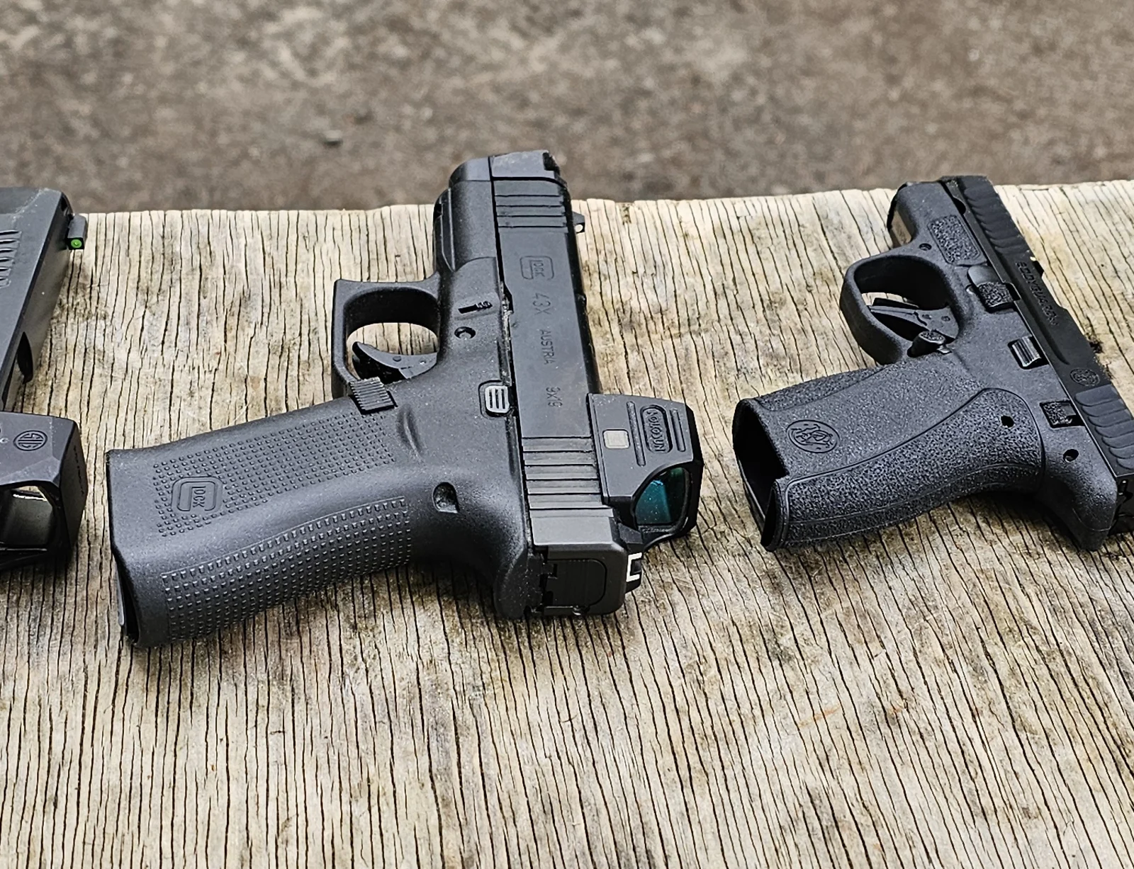 Holosun SCS Carry mounted on a Glock 43X slide, left side view on a weathered wooden range bench showing the Holosun housing and green-tinted lens