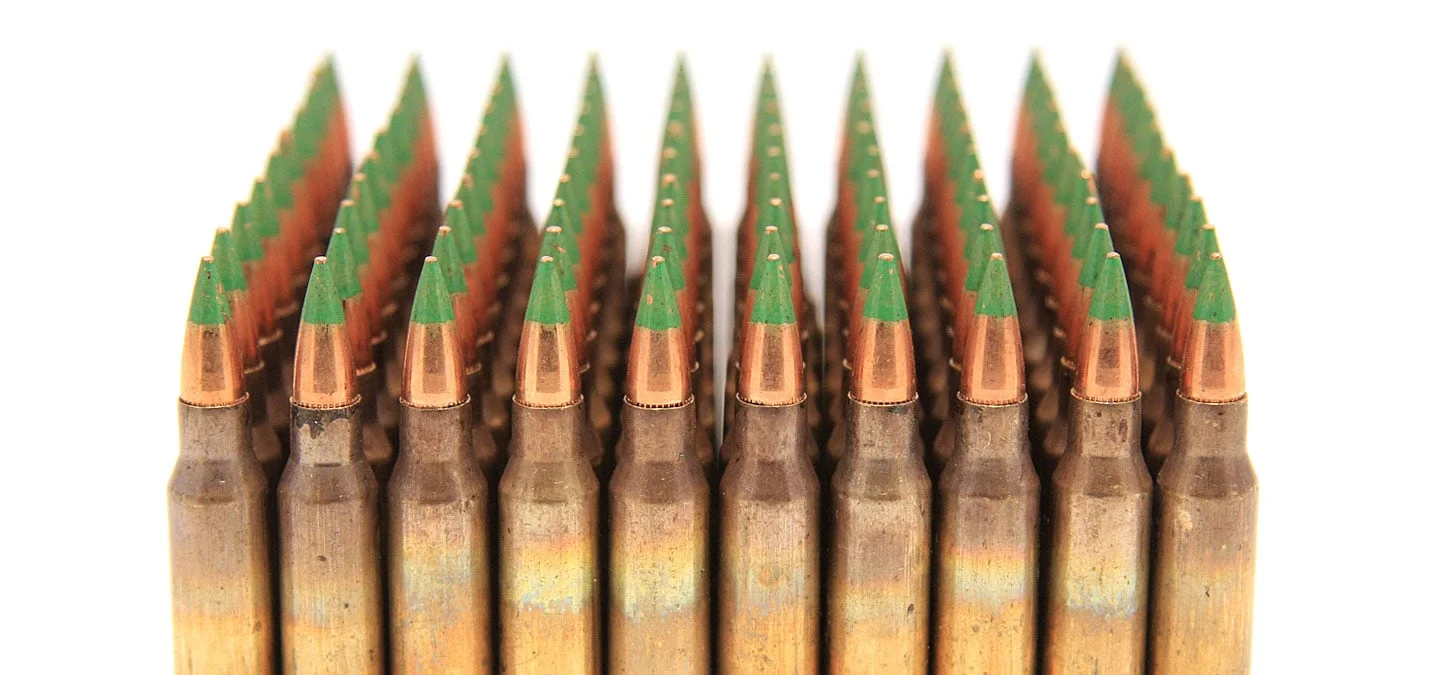 Rows of M855 green tip 5.56 NATO cartridges standing upright, showing the green-painted bullet tips