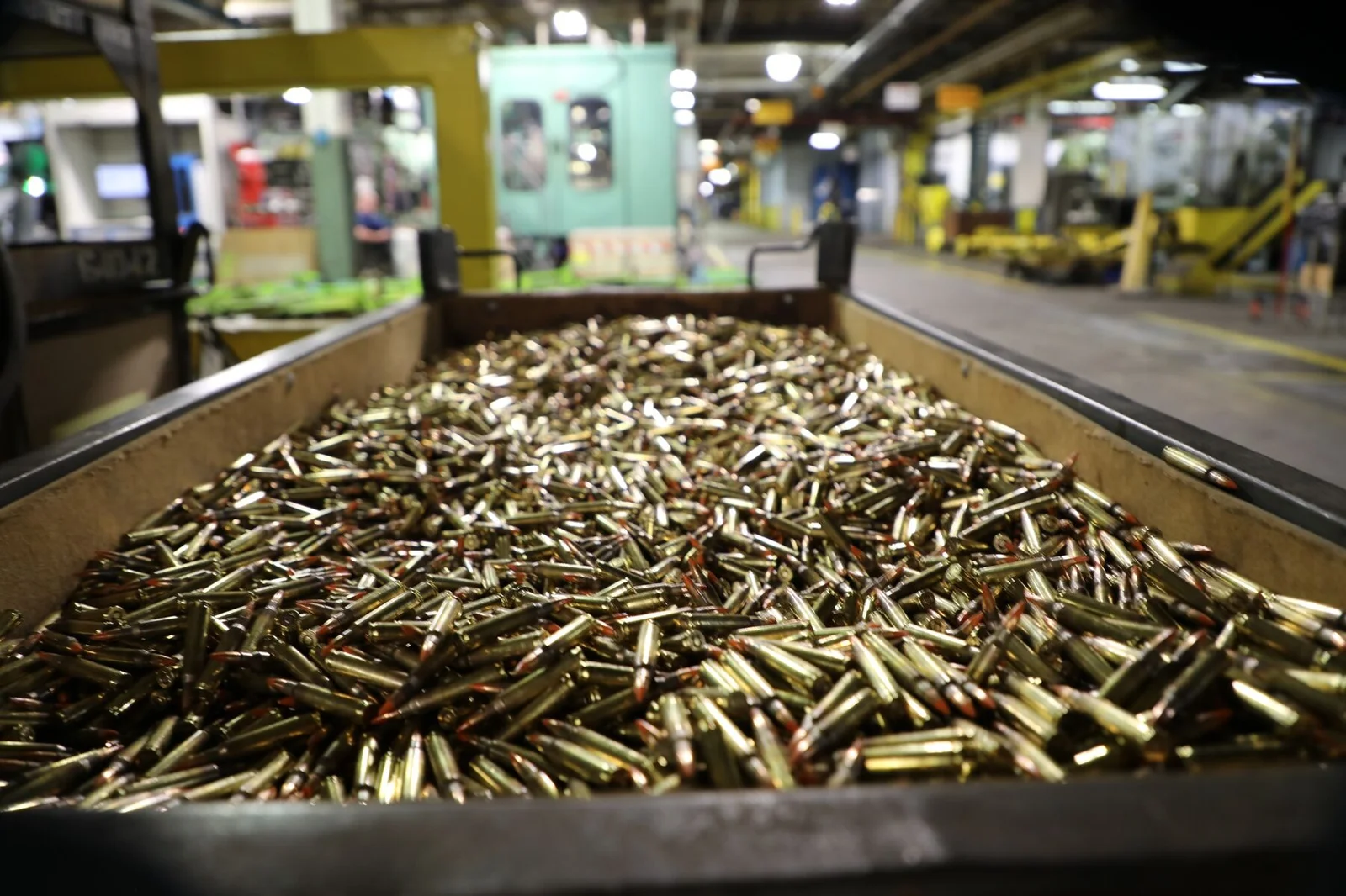 Bin filled with thousands of loaded 5.56 NATO cartridges on the production floor of an ammunition plant