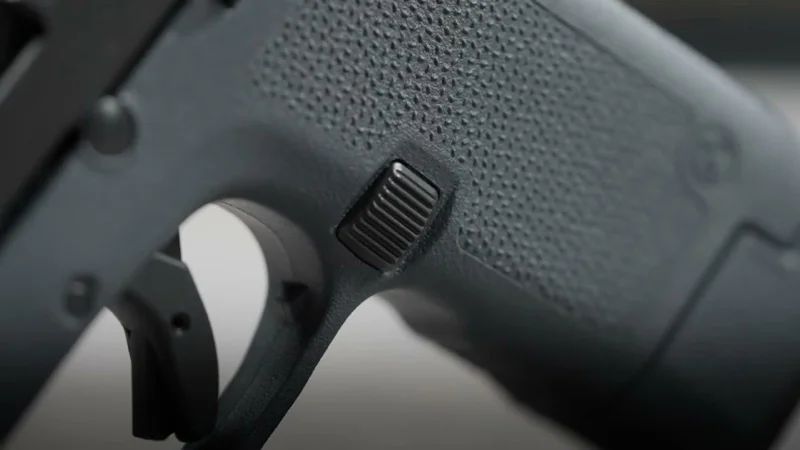 Close-up of the increased mag release surface on the Magpul EHG RG380 grip with the larger ribbed button visible against the TSP textured grip panel