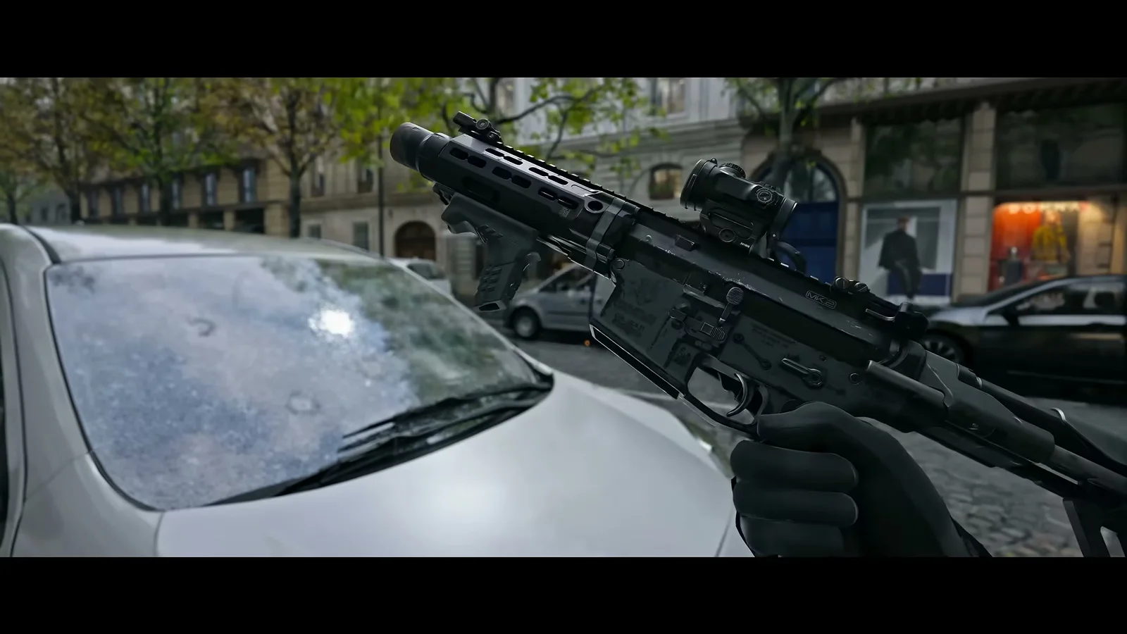 Captain Price holding a compact suppressed M4-pattern carbine with a short M-LOK handguard, vertical grip, micro red dot, and PDW stock in the Modern Warfare 4 reveal trailer