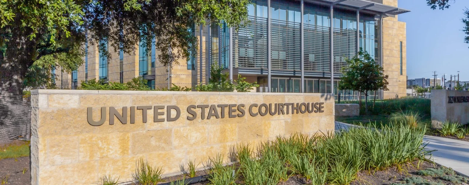 Limestone sign reading United States Courthouse in front of a modern glass federal building