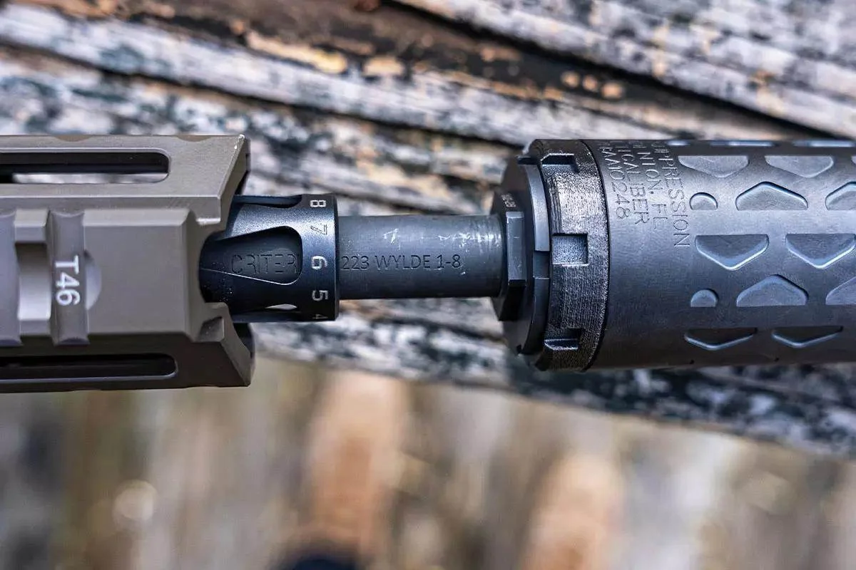 Close-up of a suppressor being threaded onto a 223 Wylde barrel with a taper mount