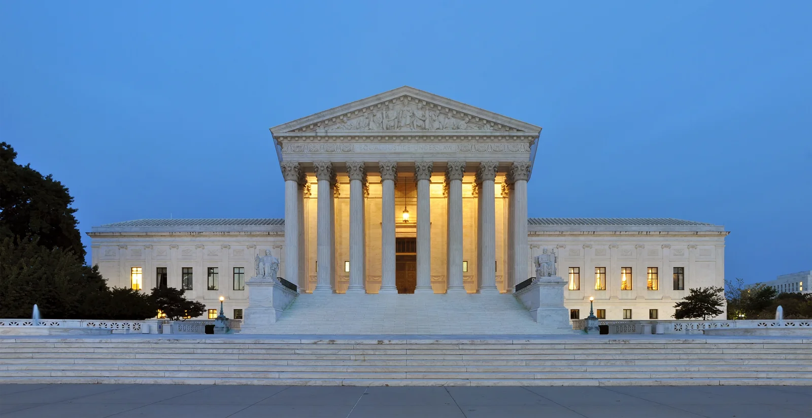 Front elevation of the United States Supreme Court building at dusk with interior lights on