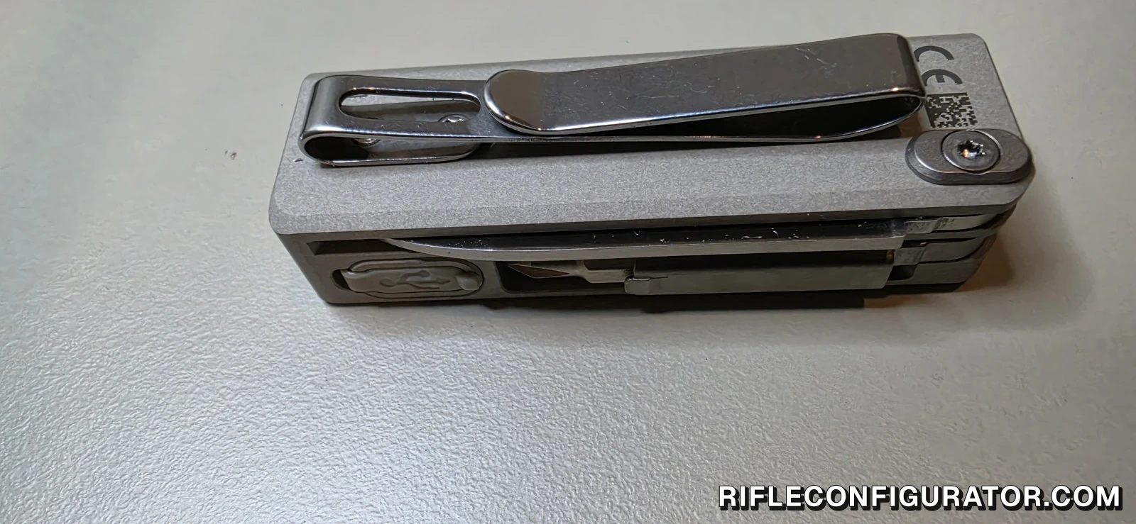 Side view of the OKNIFE MK showing the screwed-on pocket clip, the folded blade, and the USB-C port cover