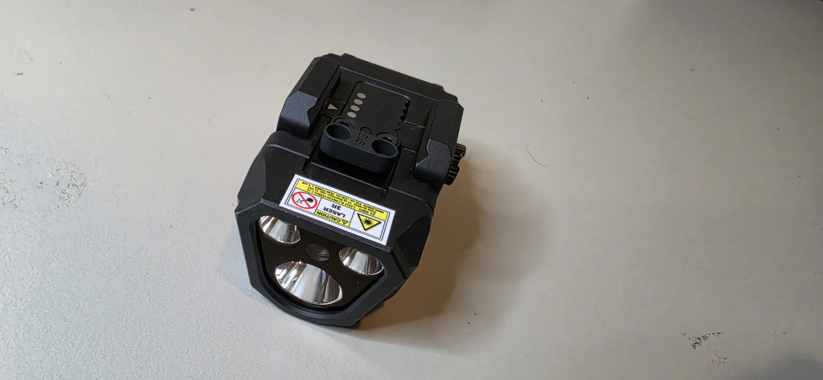 Bezel of the Olight PL X GL showing two reflectors and the laser aperture between them