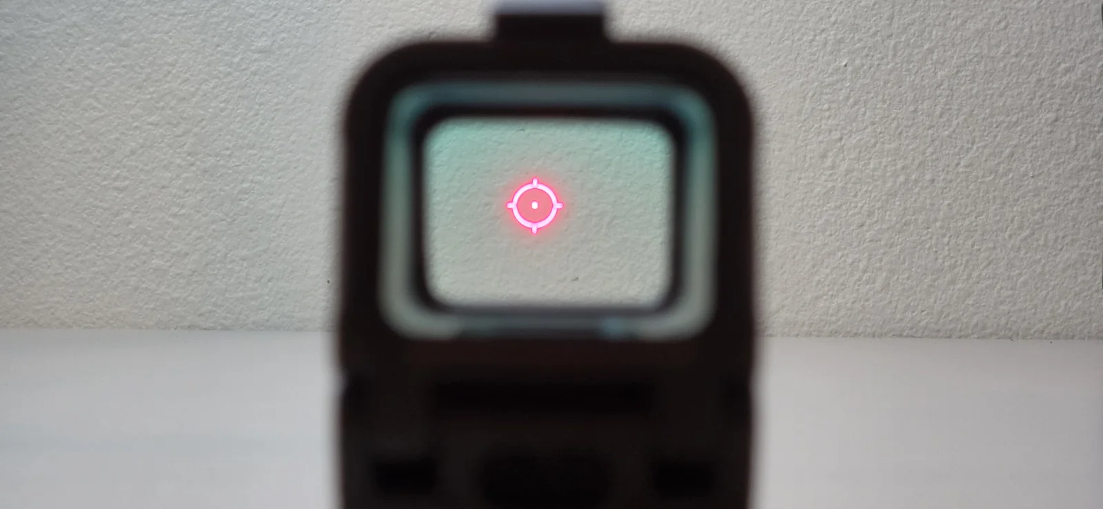 View through the Osight R indoors showing the red 65 MOA circle and 2 MOA dot against a plain white wall
