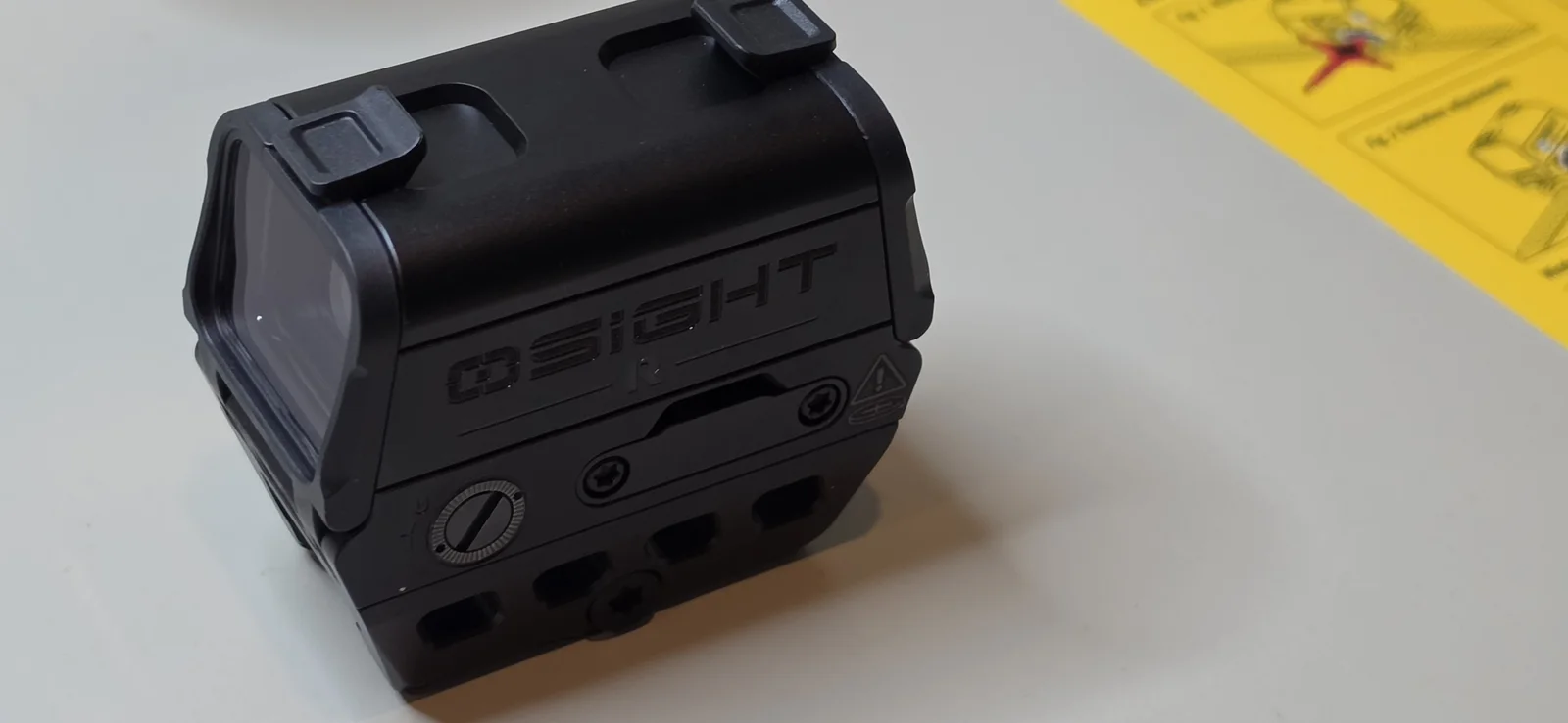 Osight R fresh out of the box on a white table, wordmark side, with flip covers closed and the instruction card beside it