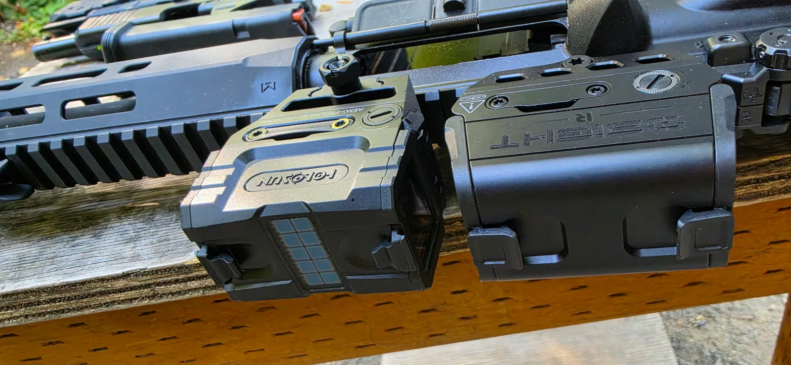 Holosun AEMS Pro X2 at left and Osight R at right, both mounted on rifles on a range bench