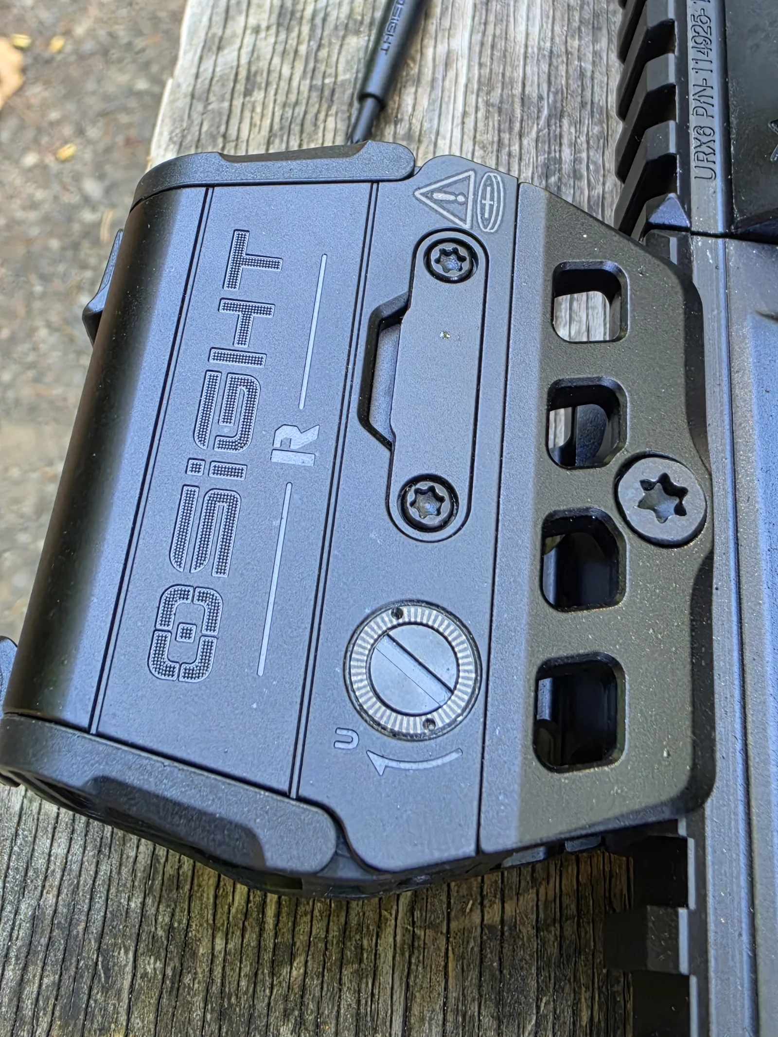 Close-up of the Osight R wordmark side showing the engraved OSIGHT R logo, the slotted elevation screw marked U, the battery tray screws, and the mount's Torx cross bolt