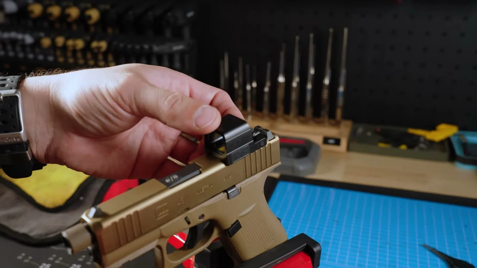 An enclosed Osight pistol red dot being mounted to a carry-size pistol slide on a workbench