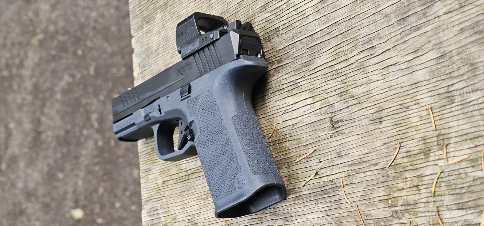 Full pistol view of the Ruger RXM with Osight XR mounted, on weathered wood