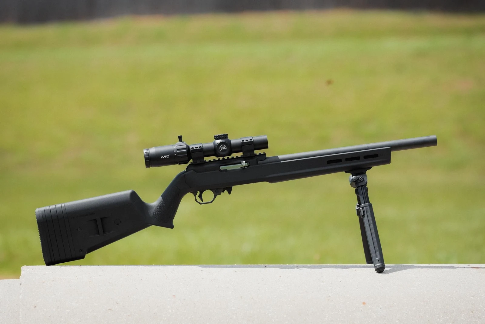 Primary Arms CLx 1-6x24 mounted on a Magpul Hunter X-22 10/22 with a bipod, resting on a concrete bench at an outdoor range