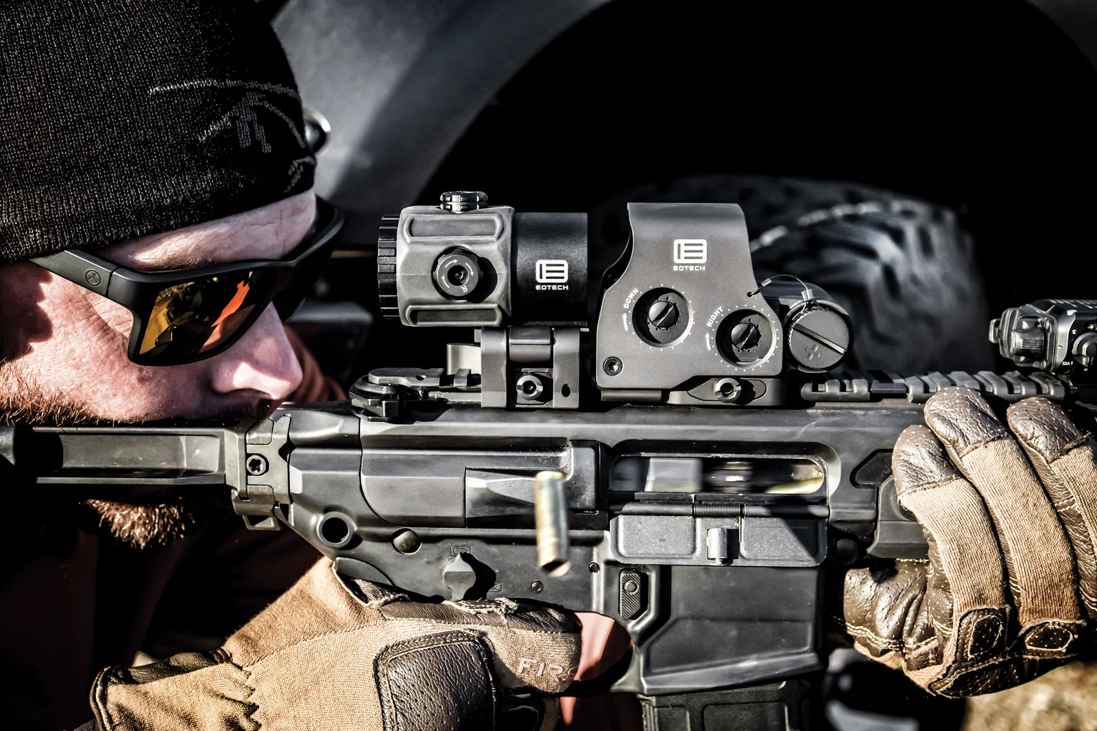 Shooter aiming through an EOTech EXPS3 holographic sight with a flip-to-side EOTech magnifier on an AR-15