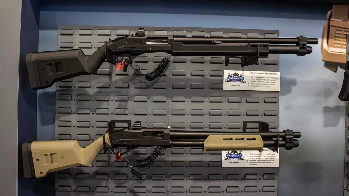 Black and FDE PSA 570 shotguns displayed side by side on a wall panel at a Palmetto State Armory booth