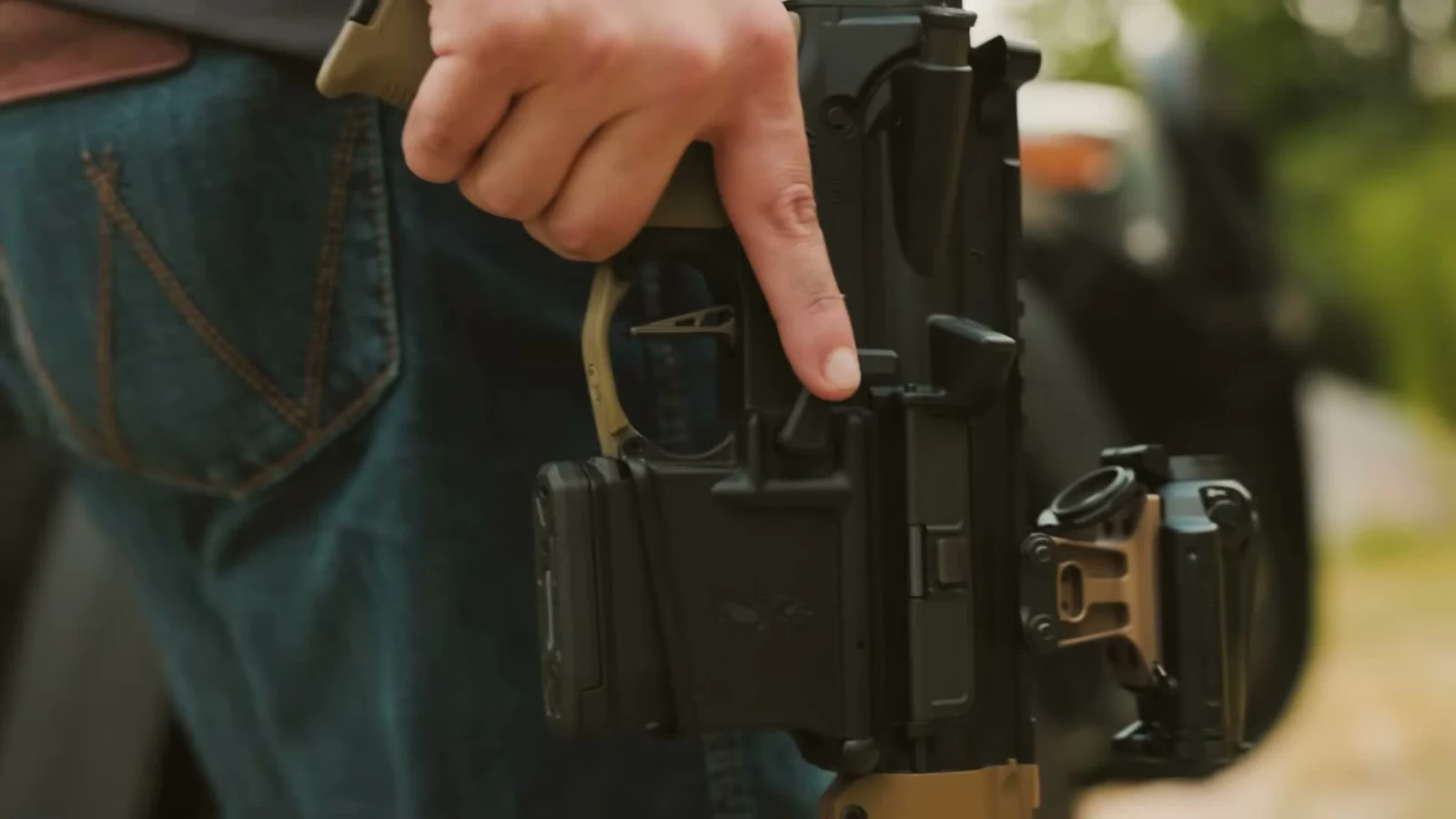 Shooter pressing the takedown pin on a California-configured PSA AR-15 with the magazine seated