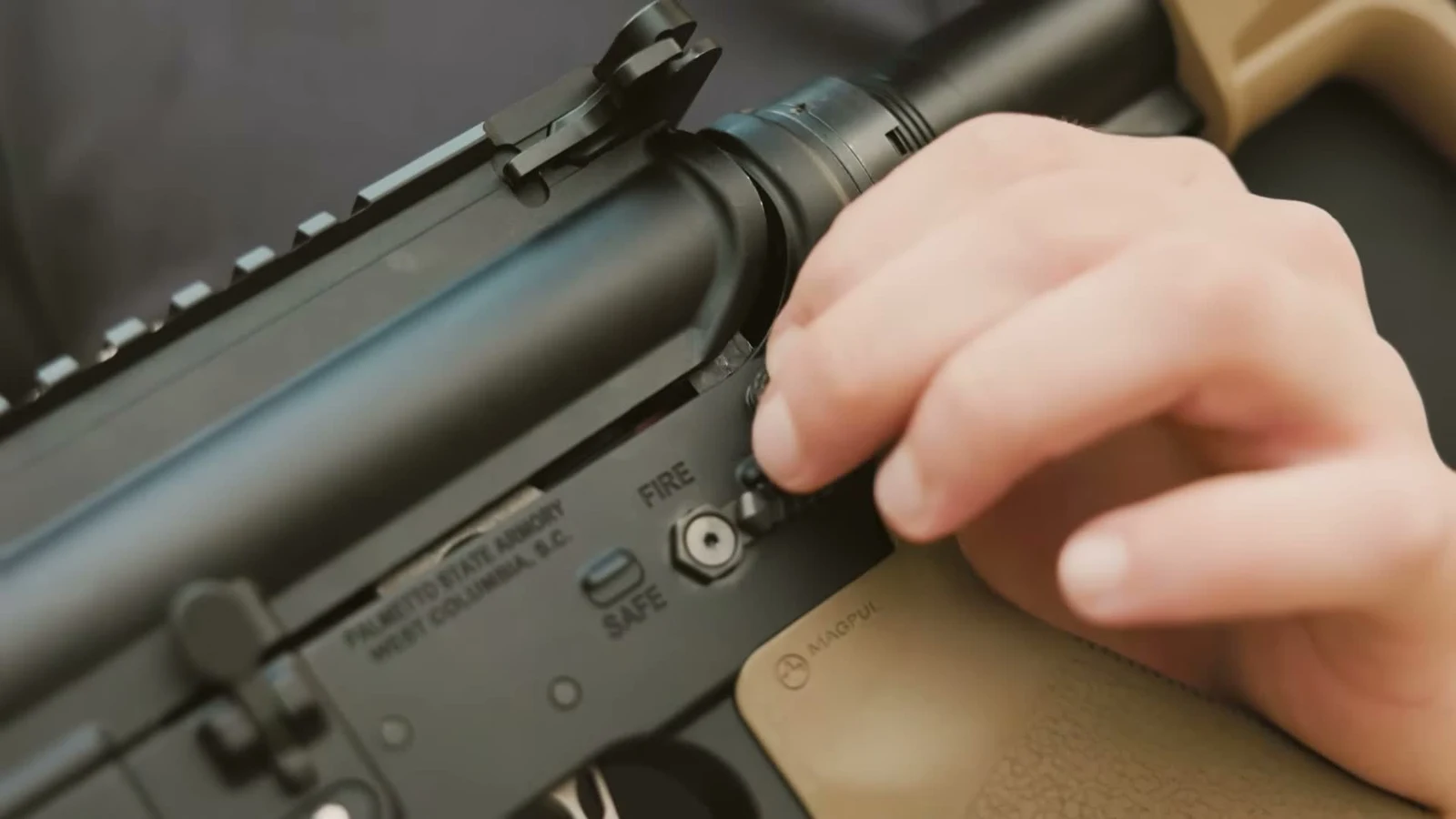 Close-up of the Palmetto State Armory West Columbia S.C. receiver rollmark with a thumb on the rear takedown pin
