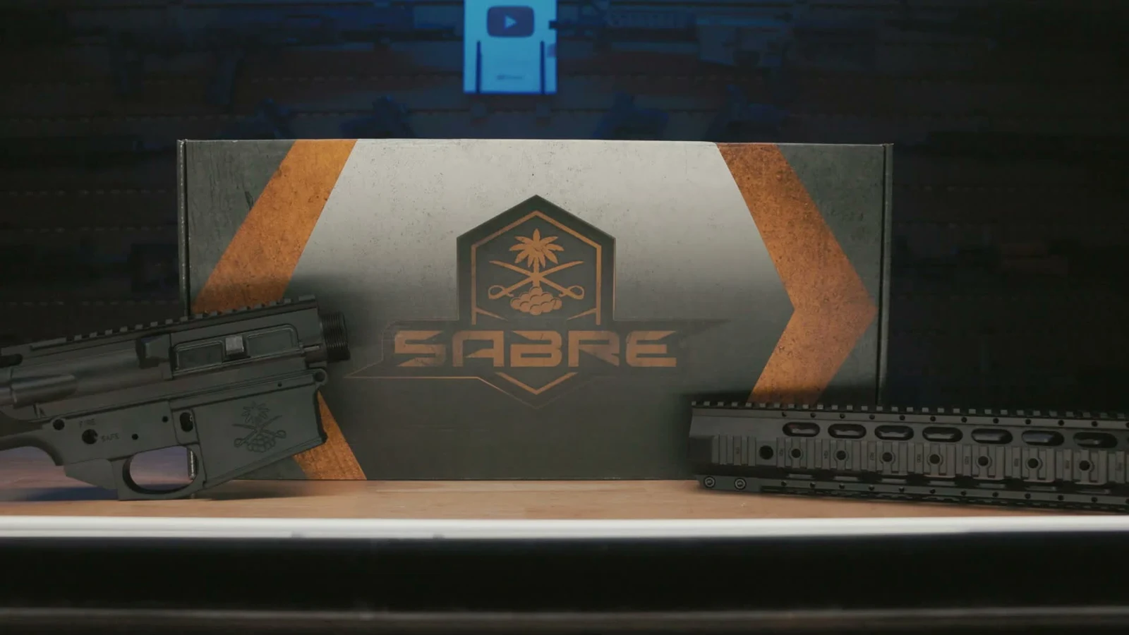 Black Sabre-10 receiver set on the left and quad rail handguard on the right flanking the Sabre-branded shipping box